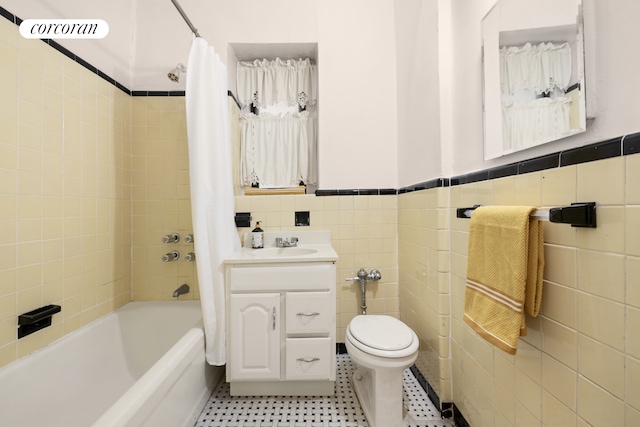 bathroom featuring tile walls, shower / bath combo, a wainscoted wall, toilet, and vanity
