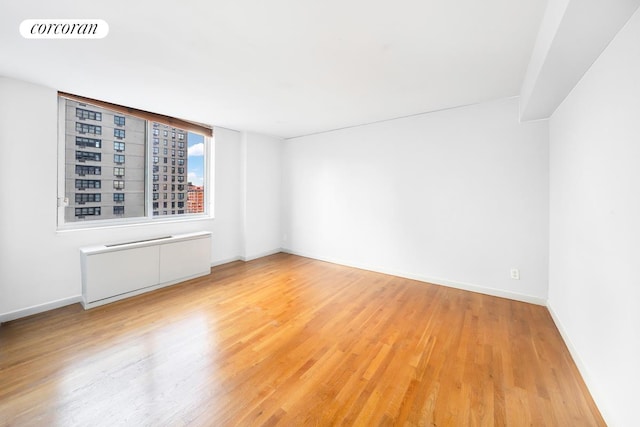 empty room featuring light wood-type flooring, visible vents, and baseboards