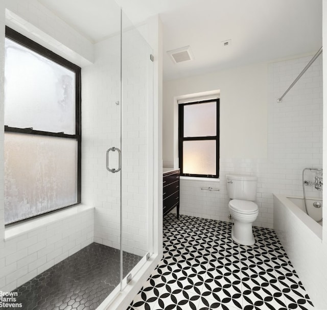 full bathroom with toilet, a stall shower, a garden tub, and tile walls