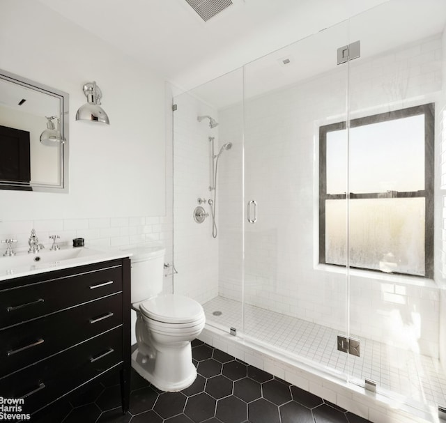 full bathroom featuring a stall shower, vanity, visible vents, and tile walls