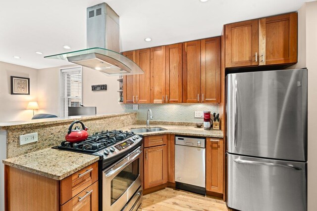 kitchen featuring kitchen peninsula, sink, island exhaust hood, light stone countertops, and stainless steel appliances