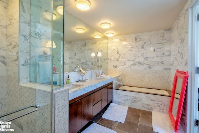 full bathroom featuring double vanity, a marble finish shower, a tub with marble appearance, tile patterned flooring, and tile walls