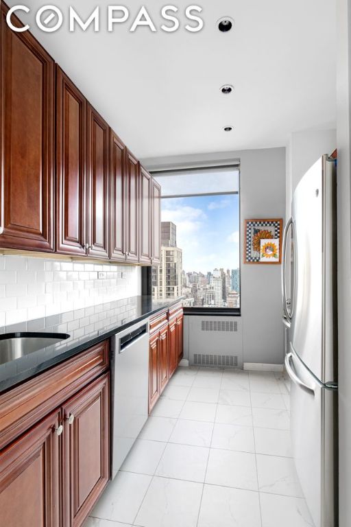 kitchen with light tile patterned floors, radiator heating unit, stainless steel appliances, and tasteful backsplash