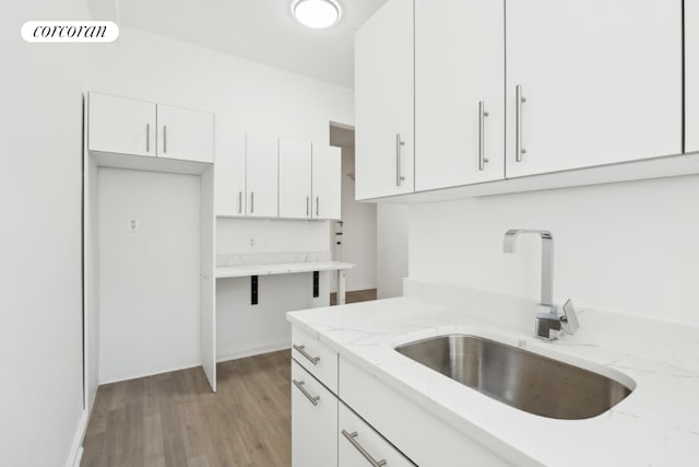 kitchen featuring white cabinetry, sink, light hardwood / wood-style flooring, and light stone countertops