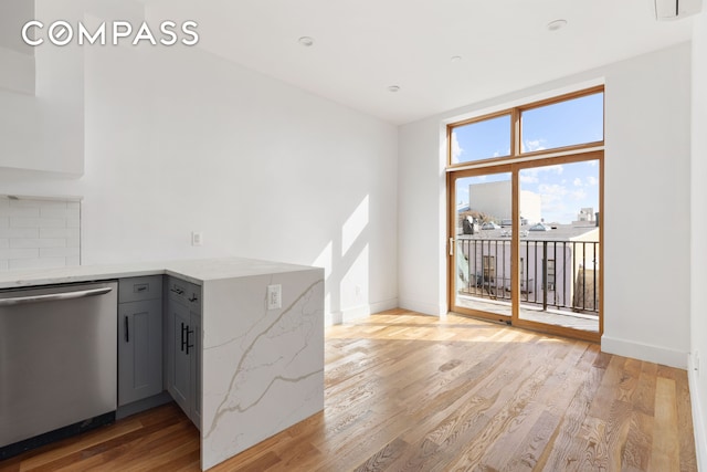 kitchen with gray cabinetry, tasteful backsplash, stainless steel dishwasher, light wood finished floors, and baseboards