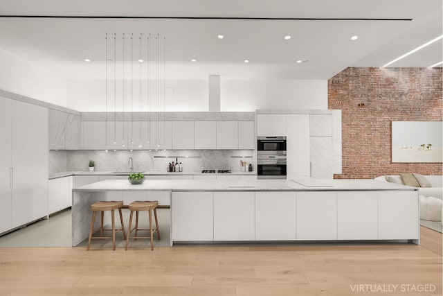 kitchen with light wood finished floors, a high ceiling, decorative backsplash, white cabinets, and modern cabinets