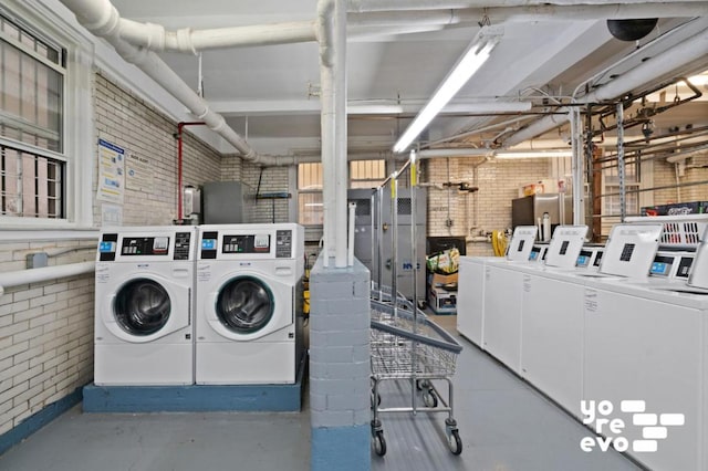 washroom with washer and clothes dryer and brick wall