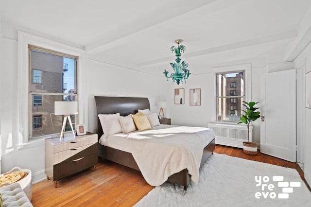 bedroom with radiator, hardwood / wood-style flooring, and beamed ceiling