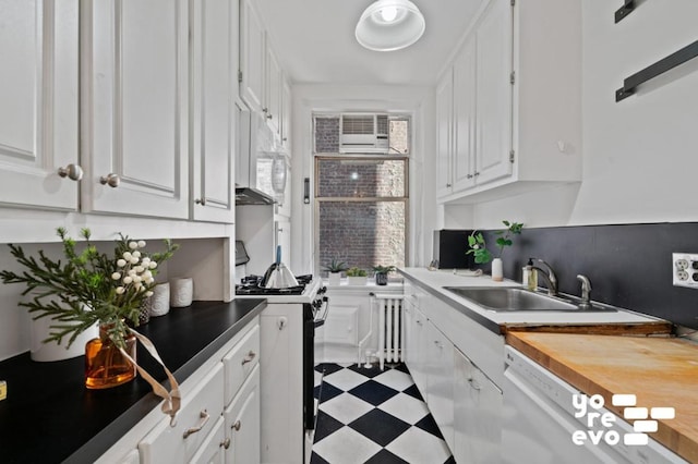 kitchen with white appliances, a wealth of natural light, white cabinets, and sink