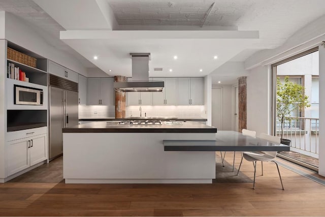 kitchen with backsplash, a kitchen island, stainless steel appliances, dark hardwood / wood-style flooring, and island range hood