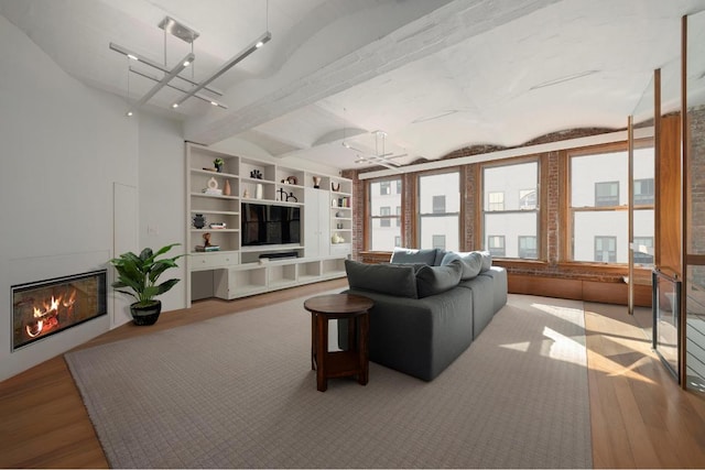 living room featuring built in shelves, brick ceiling, lofted ceiling with beams, and light hardwood / wood-style floors