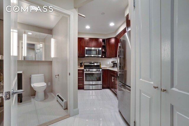 kitchen featuring a baseboard radiator, light countertops, decorative backsplash, appliances with stainless steel finishes, and dark brown cabinets