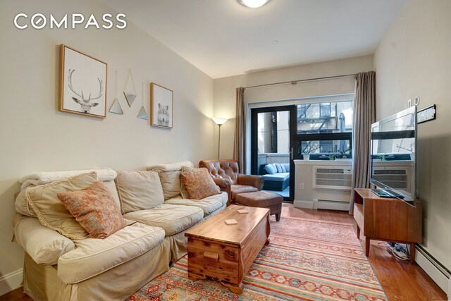 456 W 167th St Unit 1C, New York City, NY 10032 - living room with baseboard heating, wood finished floors, and a wall unit AC