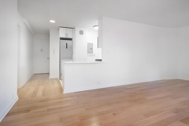 unfurnished living room featuring electric panel and light wood-type flooring