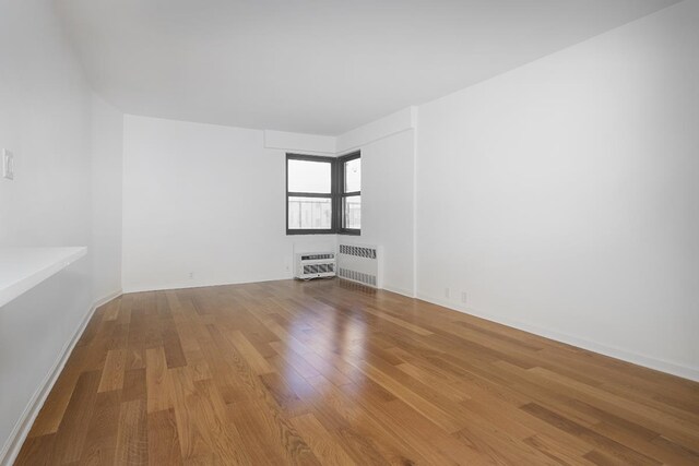 unfurnished room with radiator and light wood-type flooring