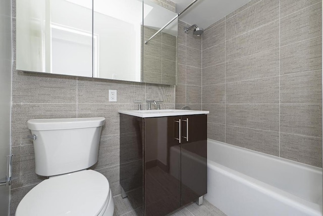 full bathroom featuring vanity, tiled shower / bath, tile walls, and toilet