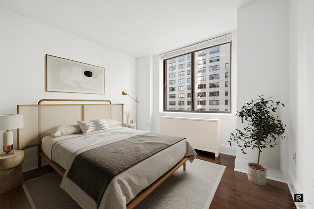 bedroom featuring radiator heating unit, dark wood finished floors, and baseboards