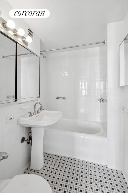 bathroom with toilet, shower / bath combination, tile patterned flooring, and tile walls