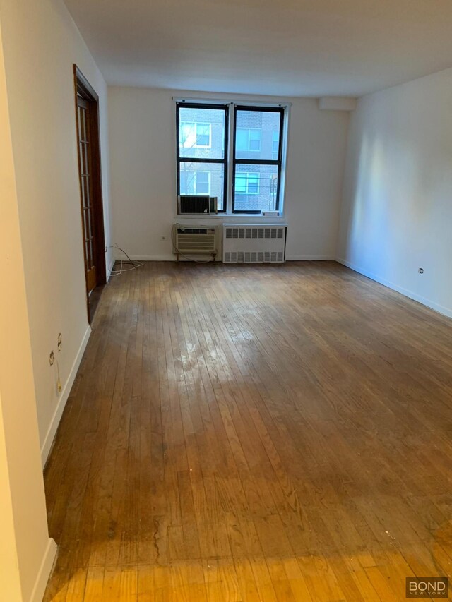 unfurnished living room featuring wood-type flooring and radiator