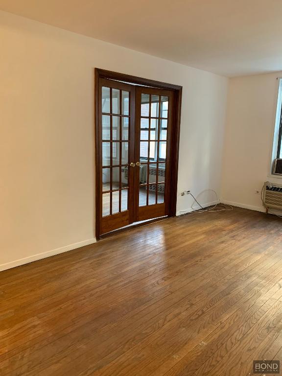 empty room with wood-type flooring and french doors