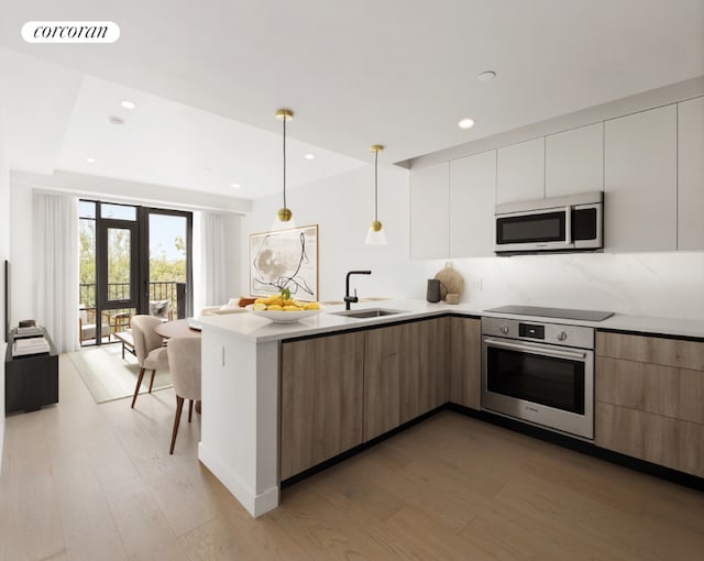 kitchen featuring hardwood / wood-style flooring, appliances with stainless steel finishes, decorative light fixtures, white cabinets, and sink