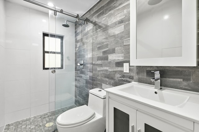 bathroom with vanity, a shower stall, toilet, and tile walls