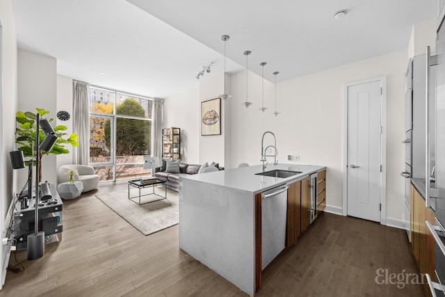 kitchen with pendant lighting, stainless steel appliances, sink, kitchen peninsula, and light hardwood / wood-style flooring