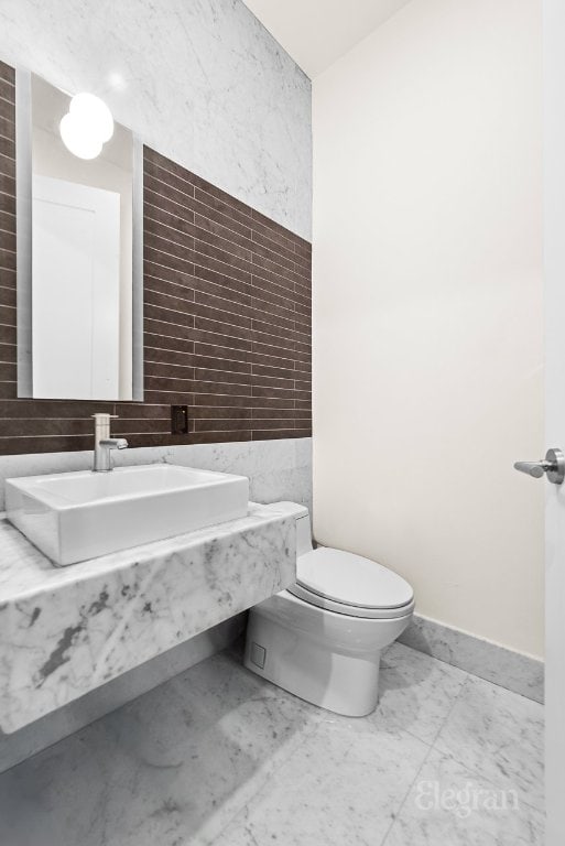 bathroom with sink, tile walls, and toilet