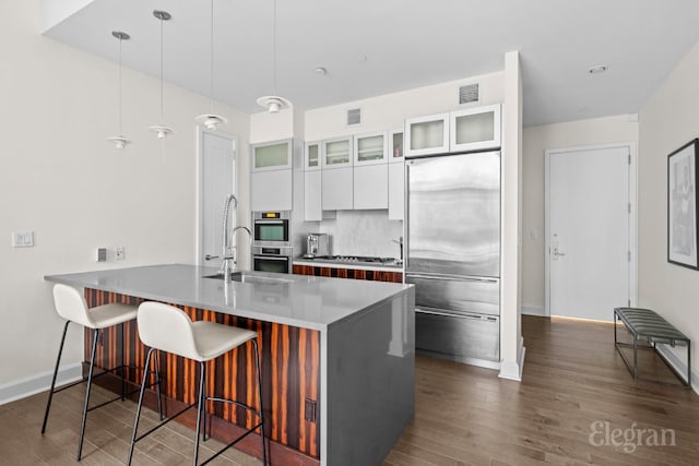 kitchen with white cabinetry, stainless steel appliances, decorative backsplash, decorative light fixtures, and a breakfast bar