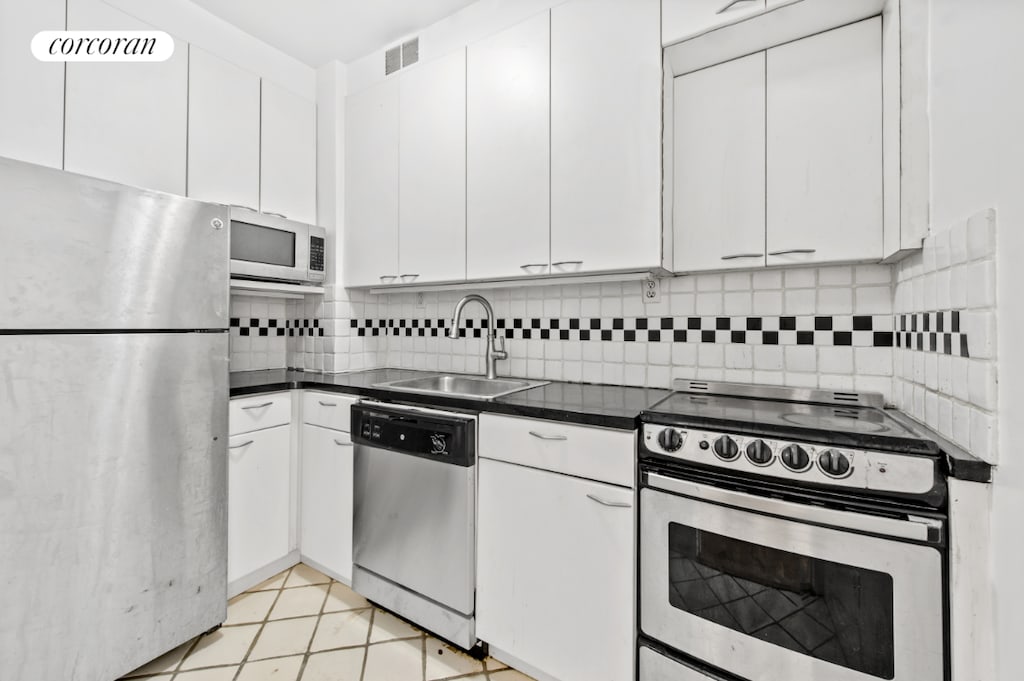 kitchen with white cabinetry, sink, backsplash, and stainless steel appliances