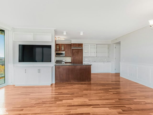 kitchen with paneled built in refrigerator, stainless steel microwave, light wood-type flooring, and glass insert cabinets