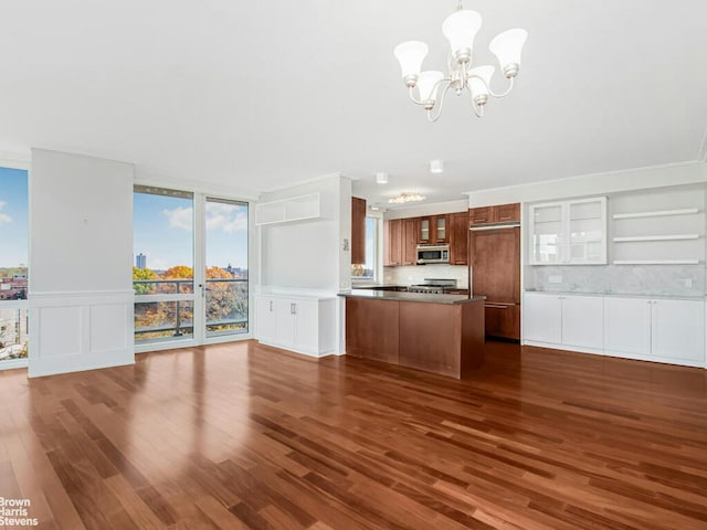 kitchen featuring stainless steel microwave, dark wood-type flooring, glass insert cabinets, open floor plan, and a chandelier