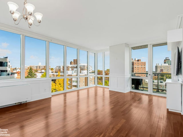 unfurnished sunroom with a view of city, radiator heating unit, and a notable chandelier