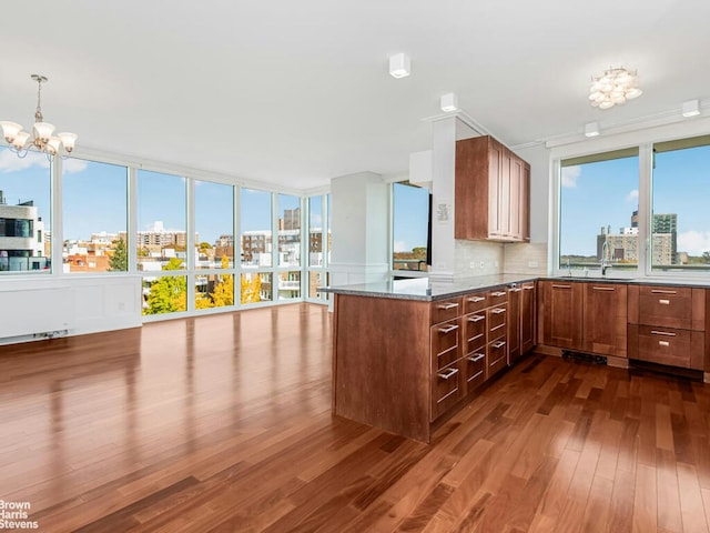 kitchen featuring a view of city, a peninsula, dark wood-type flooring, and tasteful backsplash