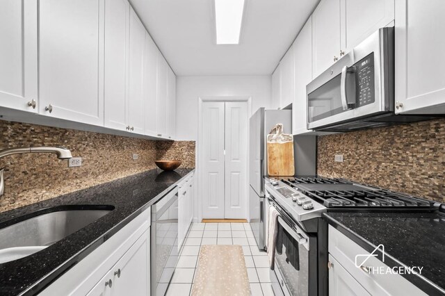 kitchen with white cabinets, stainless steel appliances, sink, backsplash, and light tile patterned flooring