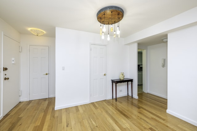 unfurnished room with an inviting chandelier and light hardwood / wood-style flooring