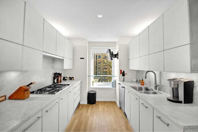 kitchen featuring appliances with stainless steel finishes, white cabinetry, a sink, and decorative backsplash