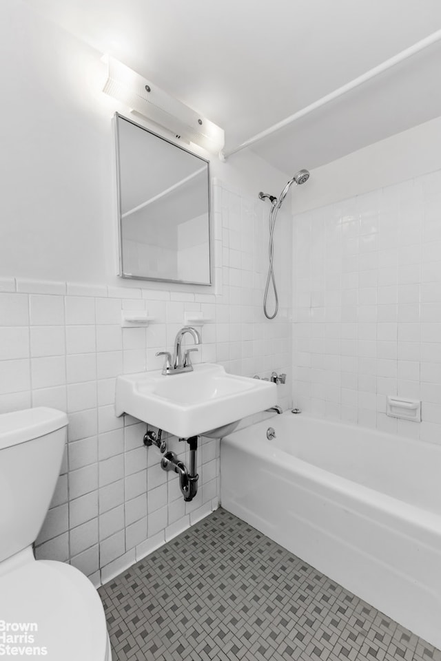 bathroom with tile patterned flooring, tile walls, toilet, and tub / shower combination