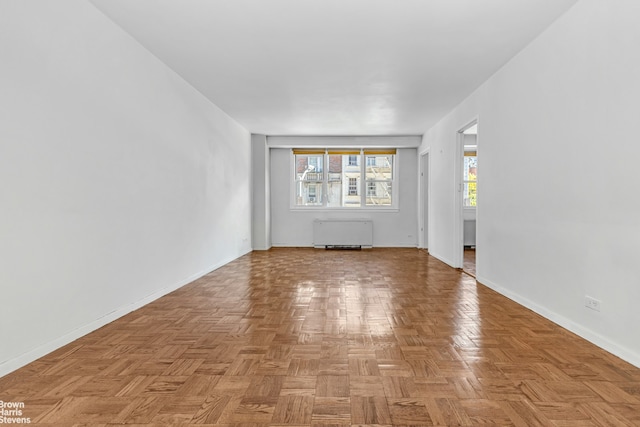 spare room featuring radiator and baseboards