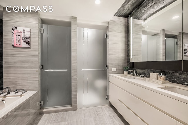 full bathroom with double vanity, a sink, a bath, and recessed lighting