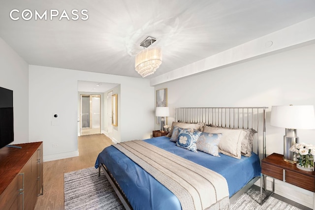 bedroom with ensuite bath, a chandelier, and light hardwood / wood-style flooring