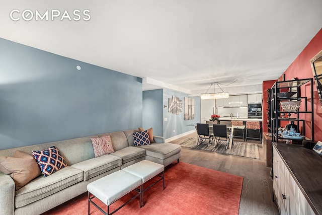 living room featuring dark wood-style floors, baseboards, and a chandelier