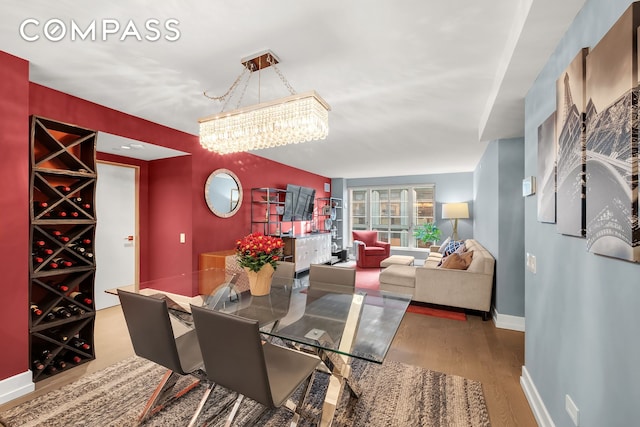 dining room with a notable chandelier, baseboards, and wood finished floors