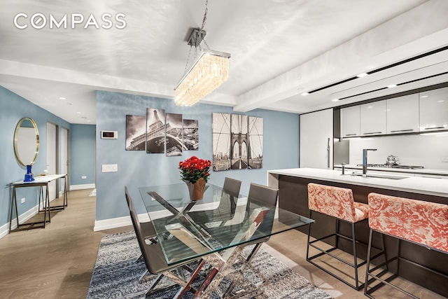 dining area with baseboards, wood finished floors, and beamed ceiling