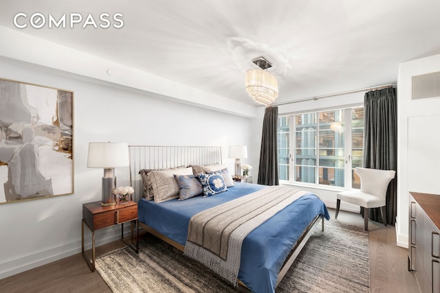 bedroom with a chandelier, wood finished floors, and baseboards