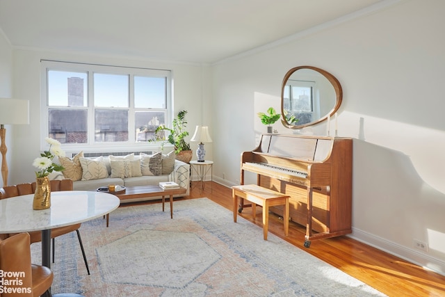 sitting room with ornamental molding, baseboards, and wood finished floors