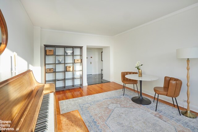 sitting room featuring baseboards, wood finished floors, and ornamental molding