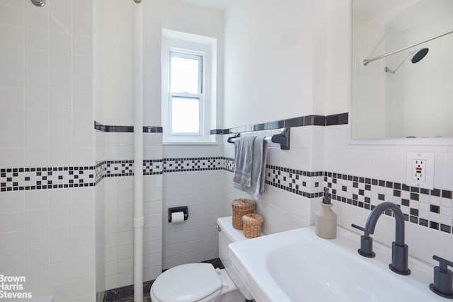 bathroom featuring toilet, tile walls, and a sink