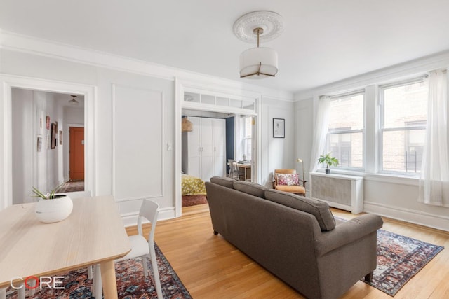 living room featuring ornamental molding, radiator, and light hardwood / wood-style flooring