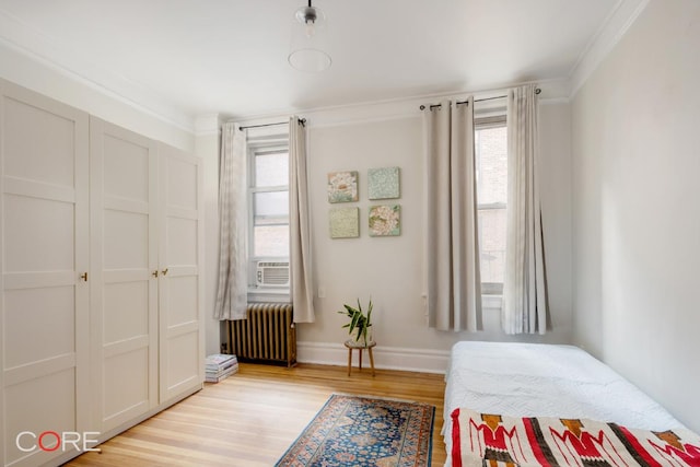 bedroom featuring ornamental molding, radiator heating unit, light hardwood / wood-style floors, and multiple windows